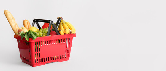 Red shopping basket full of different fresh products and baguette on white background