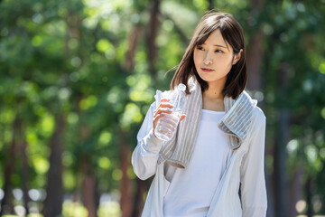 タオルで汗を拭って水分補給する女性	