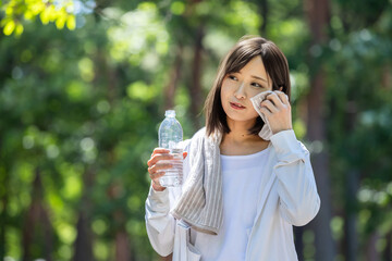 タオルで汗を拭って水分補給する女性	