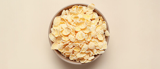 Bowl with tasty cornflakes on beige background, top view