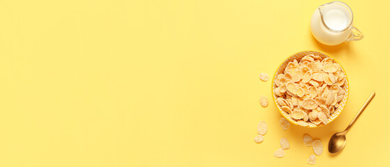 Bowl of tasty cornflakes and jug of milk on yellow background with space for text