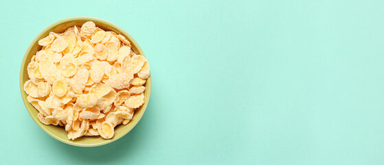 Bowl with tasty cornflakes on turquoise background with space for text