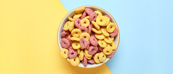 Bowl of tasty cereal rings on color background, top view