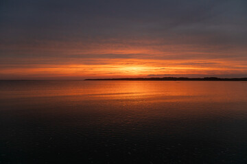 A colorful sunset of orange against the water. 