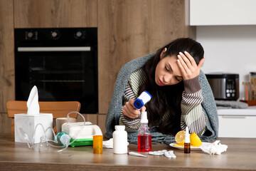 Ill young woman with infrared thermometer in kitchen