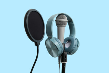Stand with professional microphone and headphones on blue background