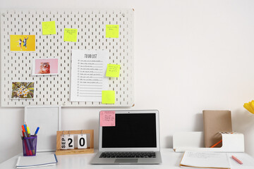 Workplace with blank laptop, pegboard and to-do list in office