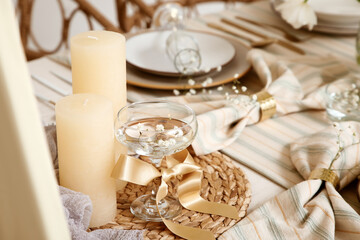 Glass of water with burning candle and spring flowers in room, closeup