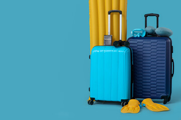 Suitcases with inflatable mattress, passport and beach accessories on blue background. Vacation...