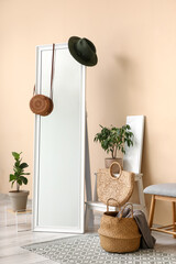Interior of living room with bench, mirror, houseplants and accessories near beige wall