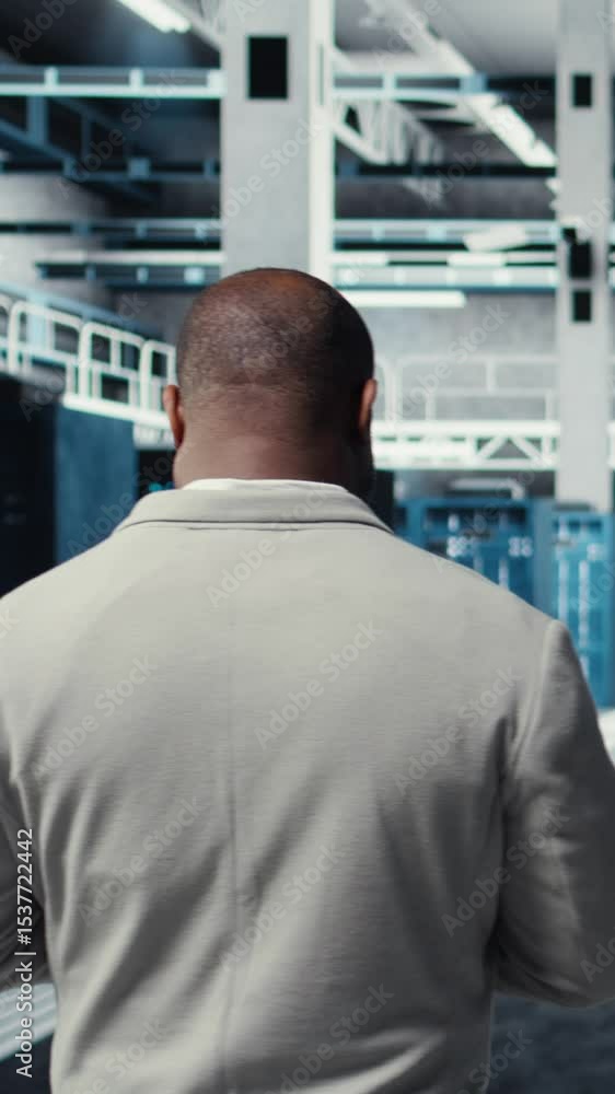 Poster vertical video admin walking in high tech data center facility, checking equipment for system stabil