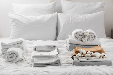 Stacks of clean bed sheets with towels and cotton flowers in bedroom
