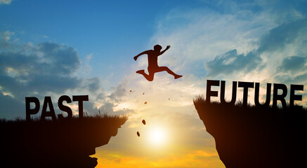 Silhouette man jumping from PAST to FUTURE wording on cliffs with cloud sky and sunrise. Go ahead and Keep go on to success Concept.