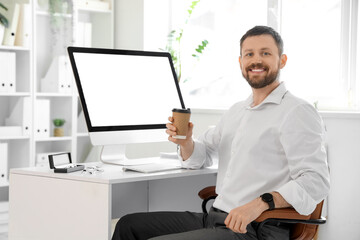Young businessman working with coffee cup and blank computer at table in office