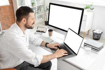 Young businessman working with blank laptop at table in office