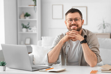 Obraz premium Young man with laptop at desk in office