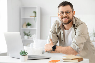 Fototapeta premium Young man with laptop at desk in office