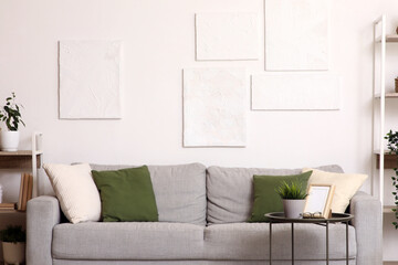 Interior of living room with grey sofa, table and paintings