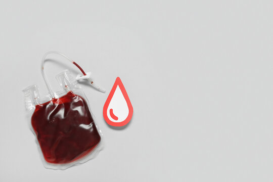 Blood pack for transfusion with red paper drop on grey background. Blood donation concept