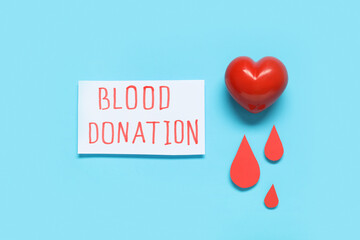 Red heart with paper drops and text BLOOD DONATION on blue background. Blood donation concept