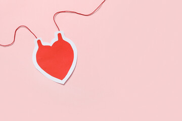 Heart-shaped blood pack for transfusion on pink background. Blood donation concept