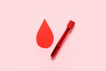Red paper drop with test tube of blood sample on pink background. Blood donation concept