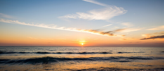 Fototapeta premium Ocean waves at sunset with colorful sky and clouds above the water.premium photo of sea and sun view for background