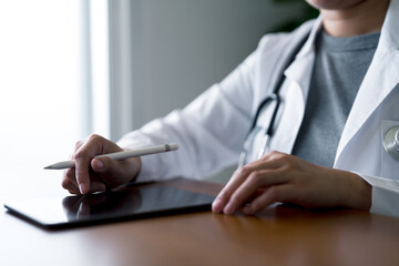Healthcare professional in white coat writing on tablet with stylus, symbolizing digital documentation, medical technology adoption, and paperless workflow in modern clinical environments.