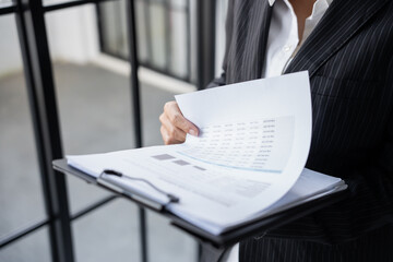 Business woman working from office taking reading and writing notes in note pad working on laptop computer  in her workstation.