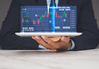 Businessman holding digital tablet with holographic stock chart, modern trading technology.