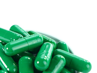 Bulk green capsule pills on a white tray isolated on white background.