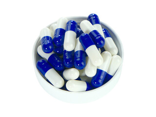Bulk blue and white capsule pills on a white tray isolated on white background.