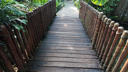 Wooden bridge leads into a lush green garden pathway