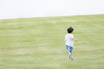 丘を駆け上る男の子の後ろ姿	