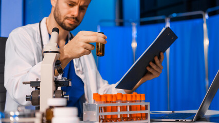 Young Caucasian male scientist works in laboratory, analyzing chemical samples with glassware and...