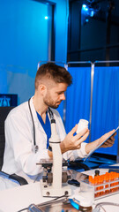 Young Caucasian male scientist works in laboratory, analyzing chemical samples with glassware and...