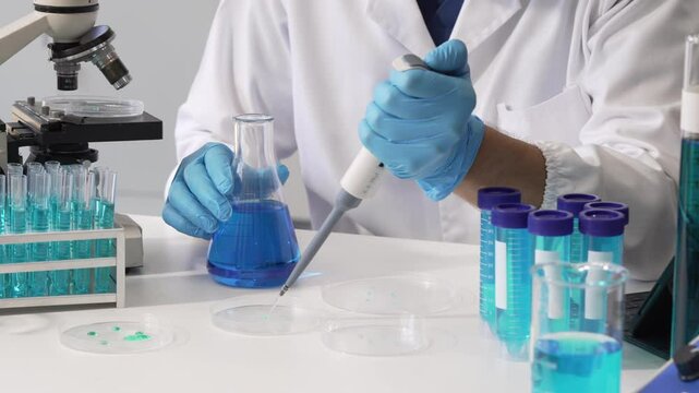 Young Caucasian male scientist works in laboratory, analyzing chemical samples with glassware and microscope. research tools, experiments, data interpretation, pharmaceutical development.