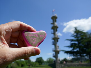 I love you heart kindness rock held with blurred observation tower in background