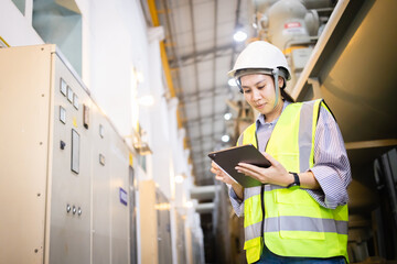 Engineer wearing safety helmet and vest inspects electric grid switchgear in industrial field using...