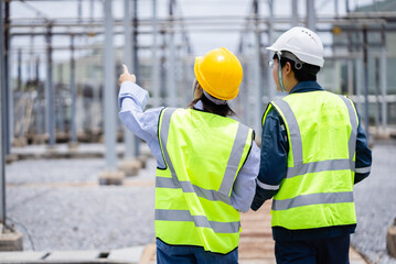 Engineer working at high voltage power substation infrastructure inspection check with safety helmet and vest ensuring operational safety and system reliability