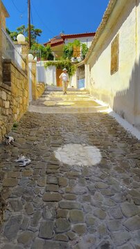 Vertical video clip of a woman walking down the steps of a pedestrian street in the town of Koroni, Peloponnese, Greece