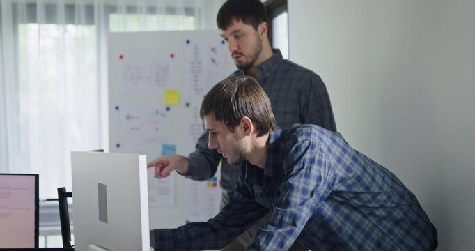 Team adult male engineer collaborate on robotic hand project using AI code solutions machine learning at tech workspace. Artificial intelligence interface, collaboration support prototype development.