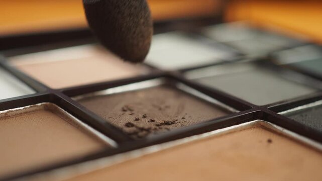Applying makeup with a brush on an eyeshadow palette