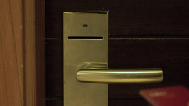 Close-up, Hand of man opening the door of an apartment or hotel room with a chip or smart card. Wrong side shows red light. Right side shows green light. Opening the door of a hotel room with a proxim
