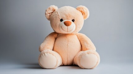 Obraz premium Plush beige teddy bear sitting against a gray backdrop
