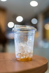 Coffee and ice little left in the glass after drink on wood table at cafe