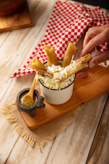 Flautas Ahogadas (Drowned Flautas) Golden tacos made with fried corn tortillas, filled with chicken or beef, and served in a glass or cup containing salsa or broth, lettuce, sour cream, and cheese.