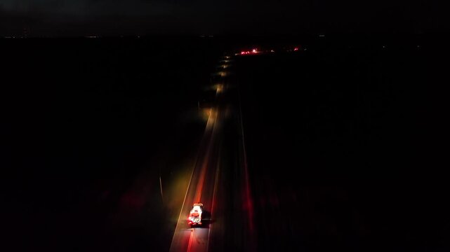 Flashing lights of fire truck driving on intersection road at night. Suburb district of american town. Accident scene after car crash in United States. Lighting lantern along road. Aerial wide shot.