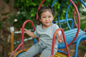happy toddler baby girl sliding and playing at playground