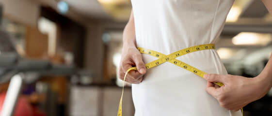Obraz na płótnie Canvas Diet and dieting. Beauty slim female body use tape measure on fitness. Woman in exercise clothes achieves weight loss goal for healthy life, crazy about thinness, thin waist, nutritionist.
